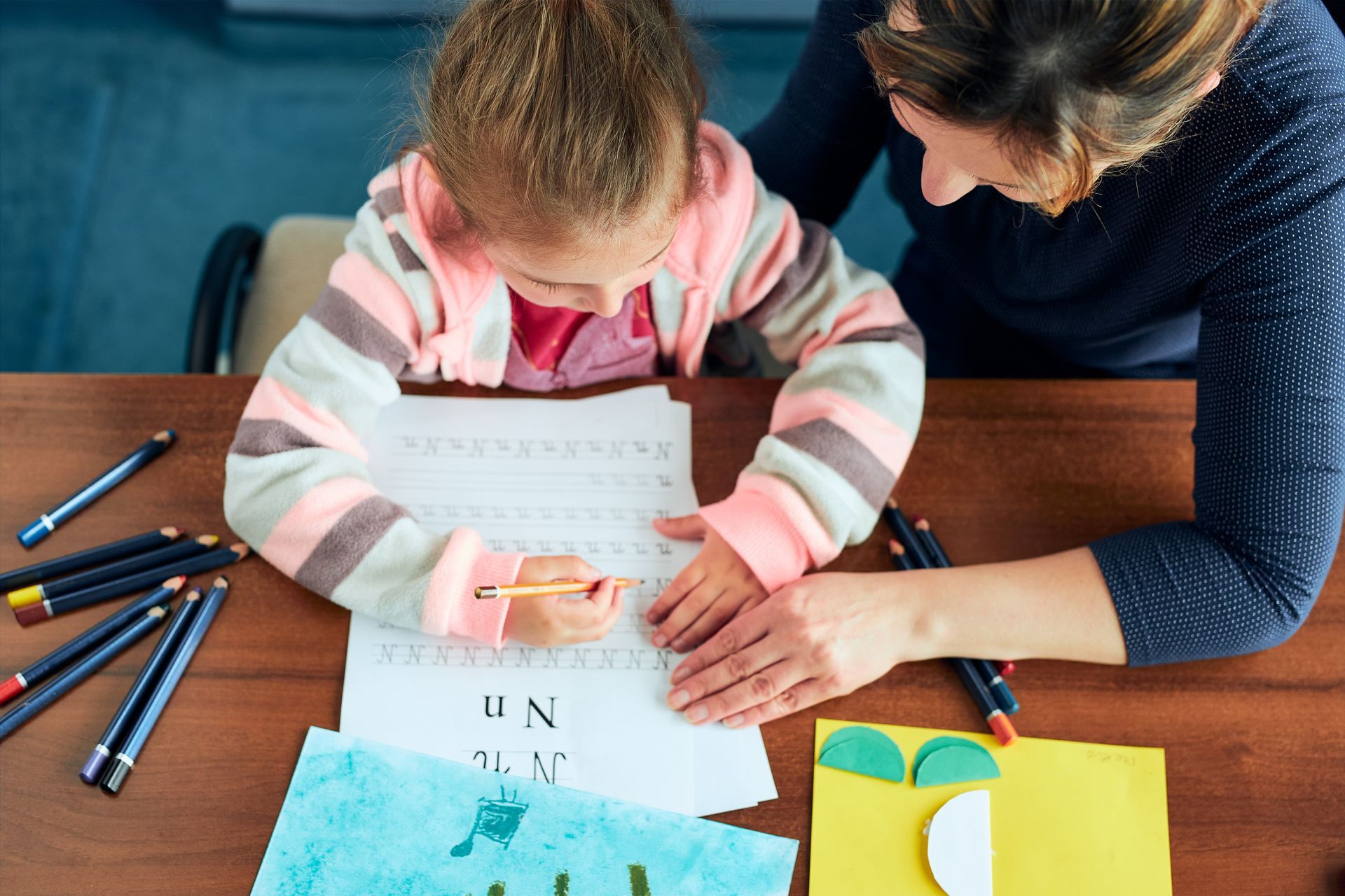 A teacher is helping a child to write. A teacher is helping a child to write.
