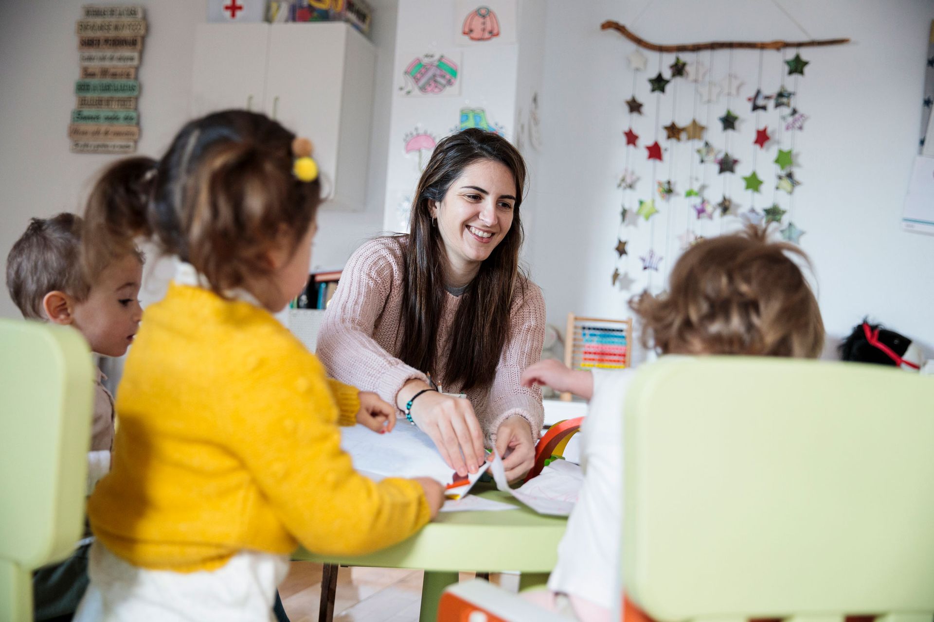 Picture of a kindergarten teacher with her students at school.
