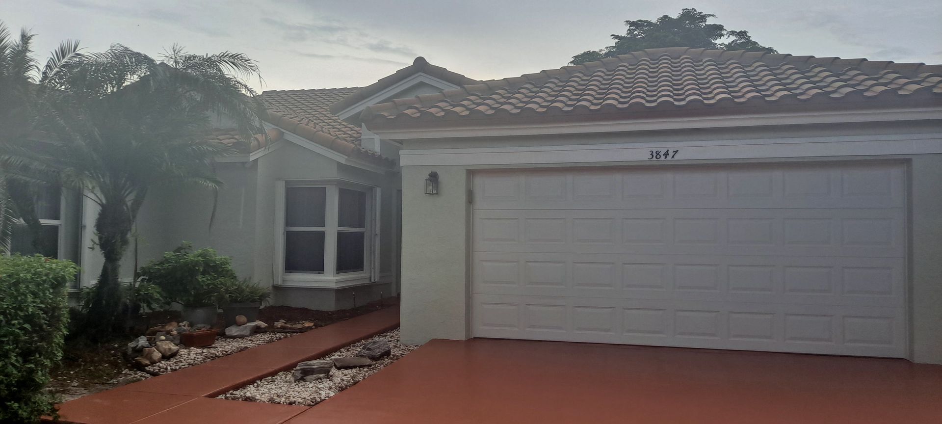 Single-story house with white garage, red driveway, and a landscaped front entry