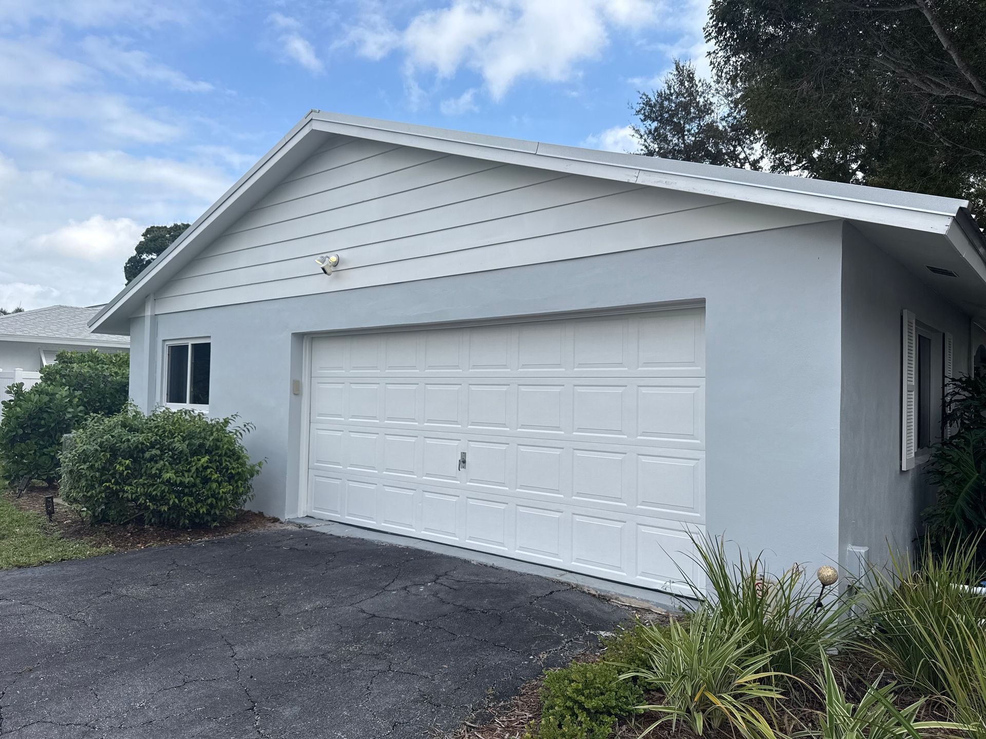 White single-story house with a two-car garage and gray driveway under a cloudy sky