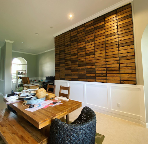 Dining room with wood table and chair, white wainscoting, and a large woven wood accent wall.