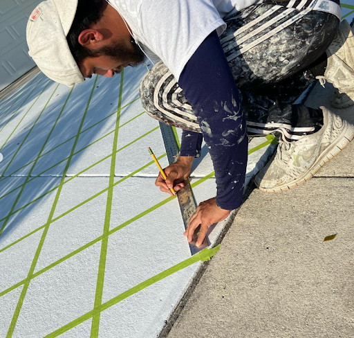 Worker measuring and marking a rooftop membrane with green chalk lines and a ruler