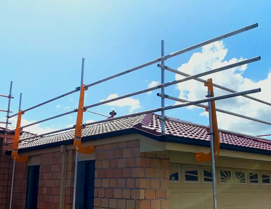 Scaffolding is being installed on the roof of a house.