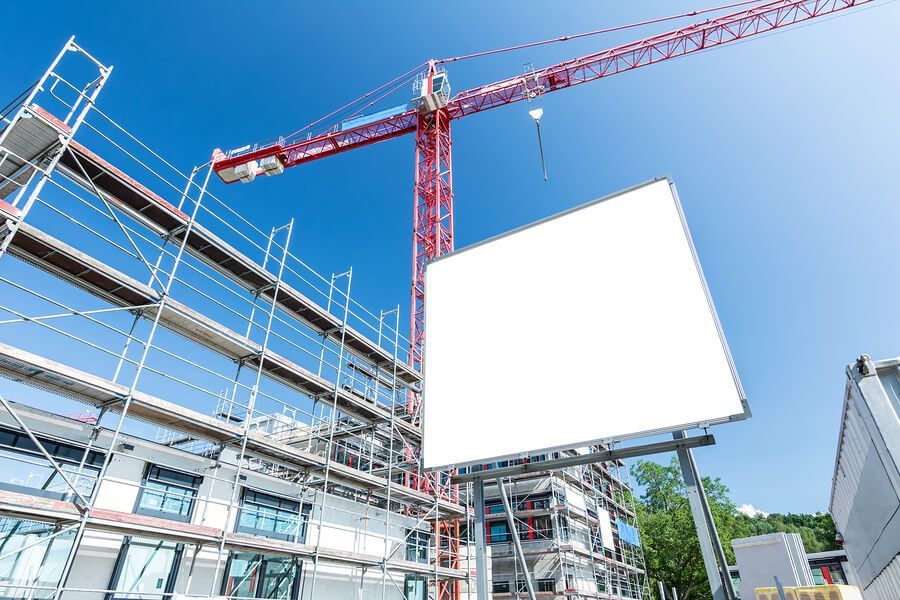 a construction site with a crane, scaffolding and a billboard