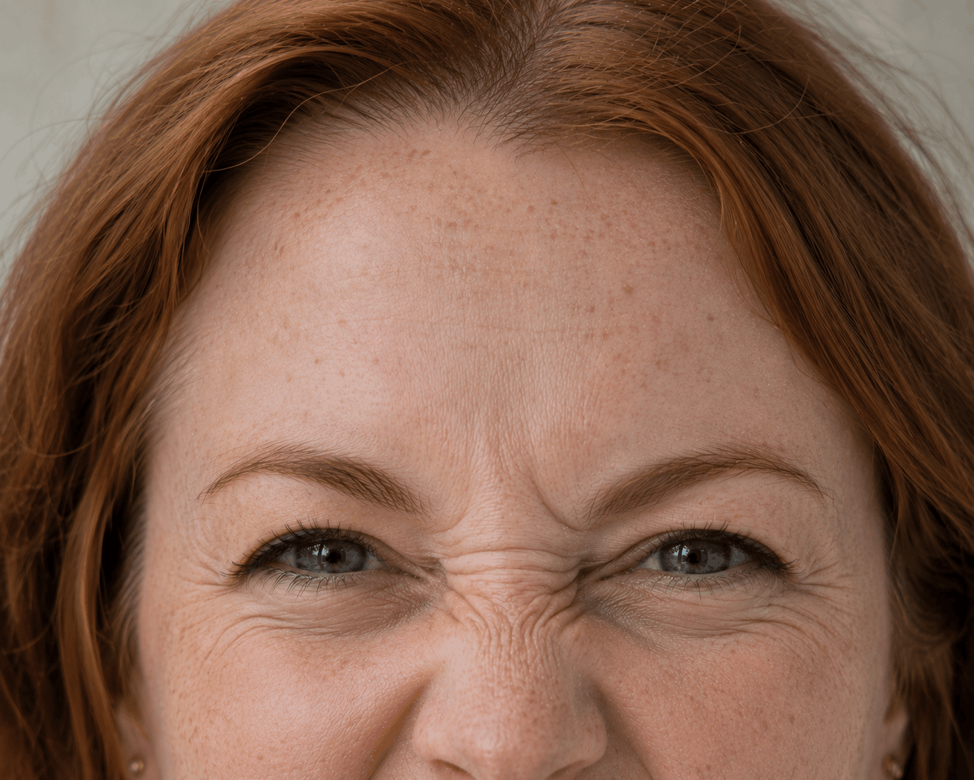 Close-up of a person’s eyes and forehead, with brown hair and a slight squinting smile