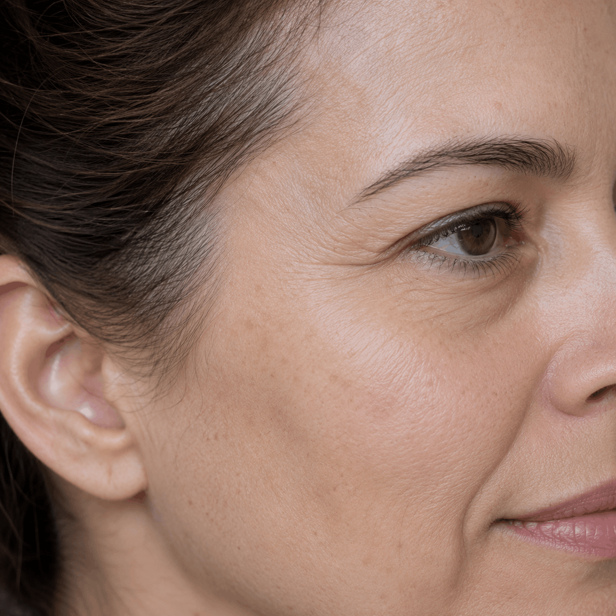 Close-up side profile of a person’s face with a neutral expression against a plain background
