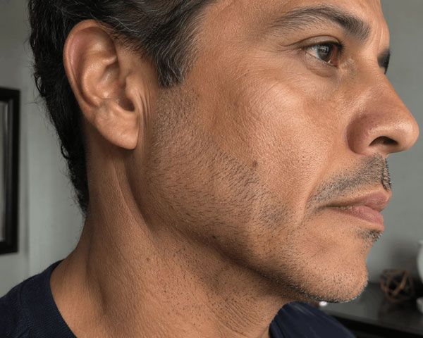 Close-up profile of a man indoors, looking right, with a neutral expression.