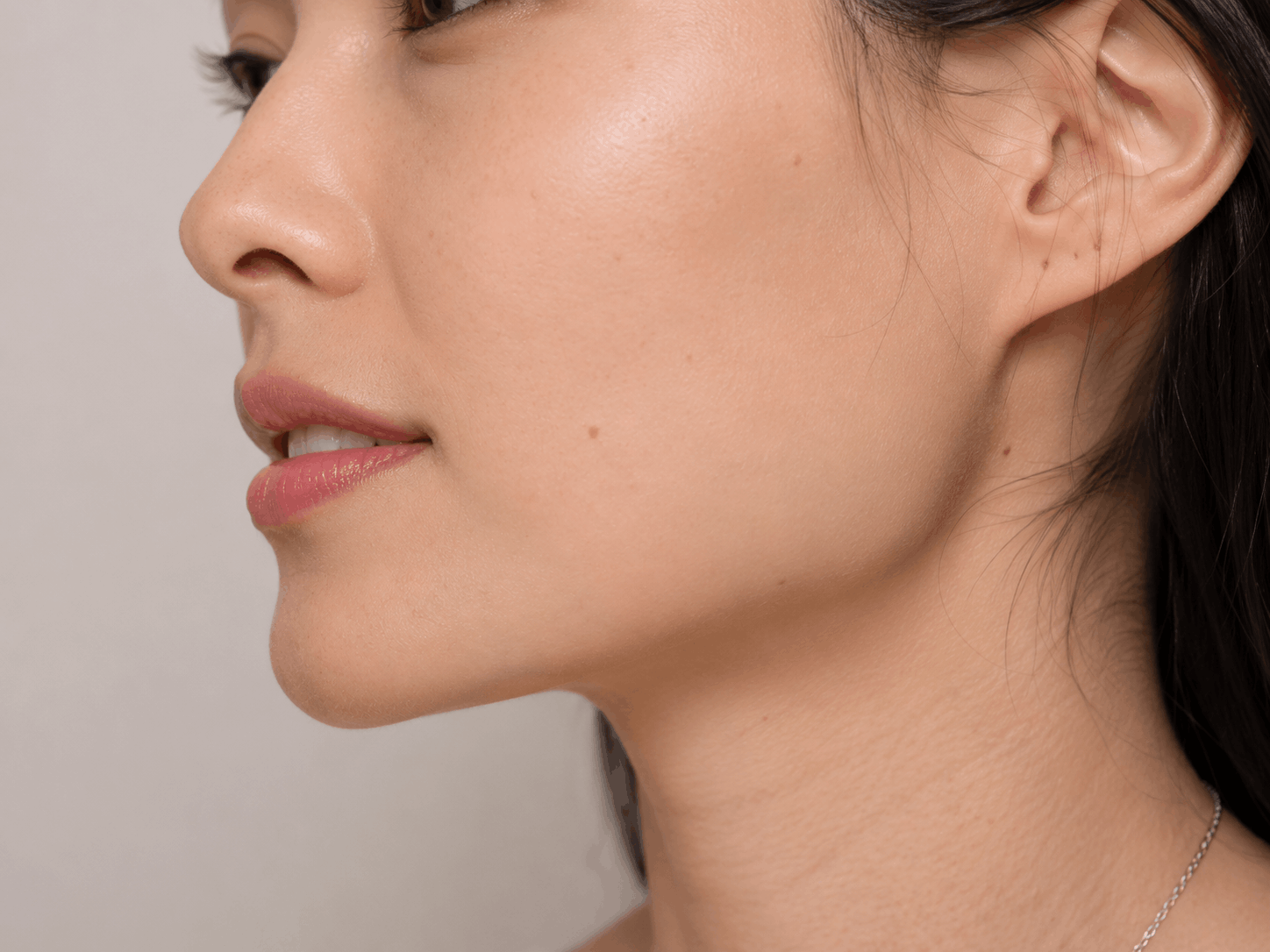 Side-profile portrait of a person with smooth skin and neutral expression against a light background