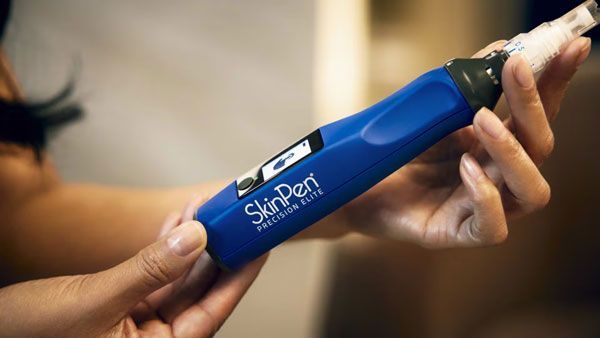 Hands holding a blue SkinPen microneedling device with a white tip