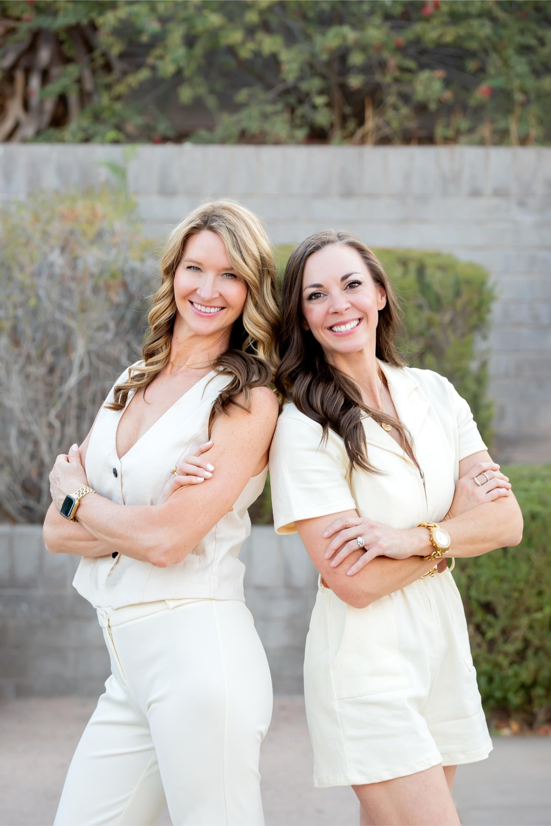 Six women stand outdoors by a building, wearing dresses in white, striped, and coral tones.