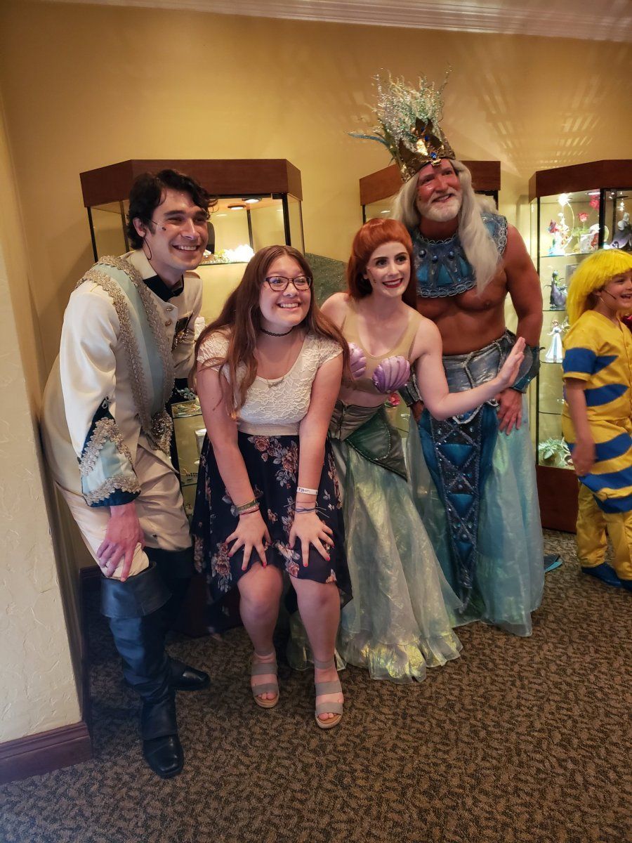 People pose with Little Mermaid characters; Prince Eric, Ariel, and King Triton.