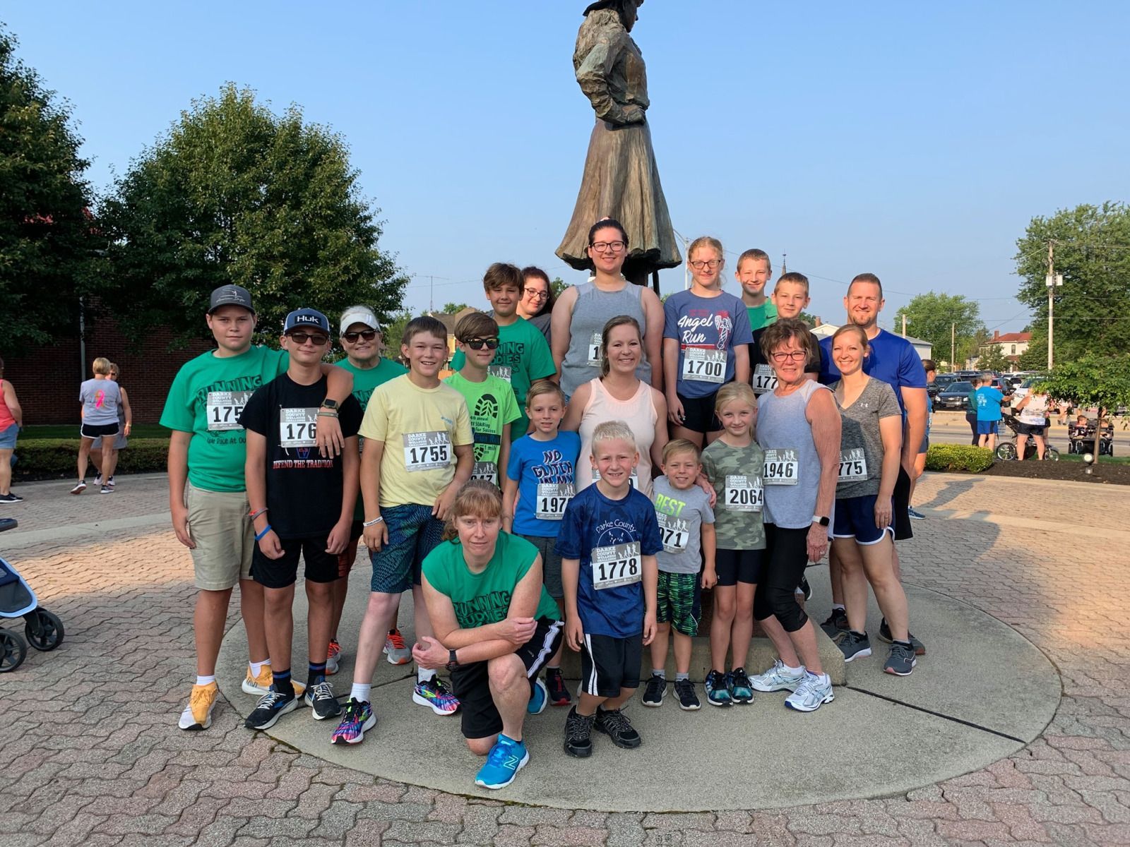 Group of runners in various colors pose with a statue before a race.