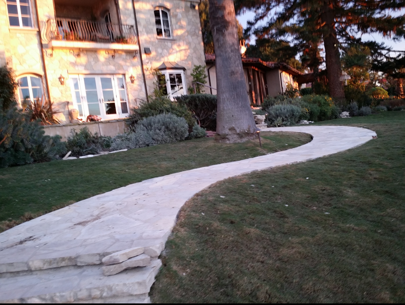 A curved walkway leads to a large house