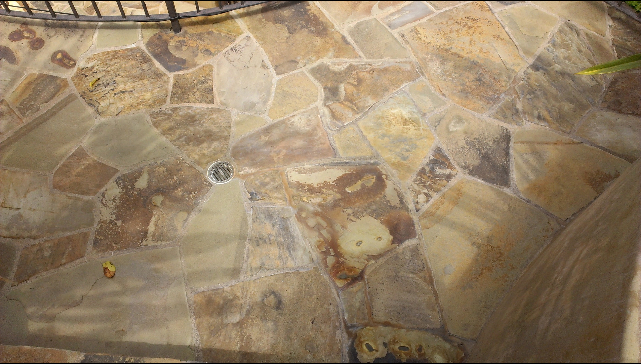 A close up of a stone floor with a drain on it.