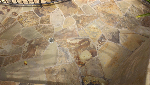 A close up of a stone floor with a drain on it.