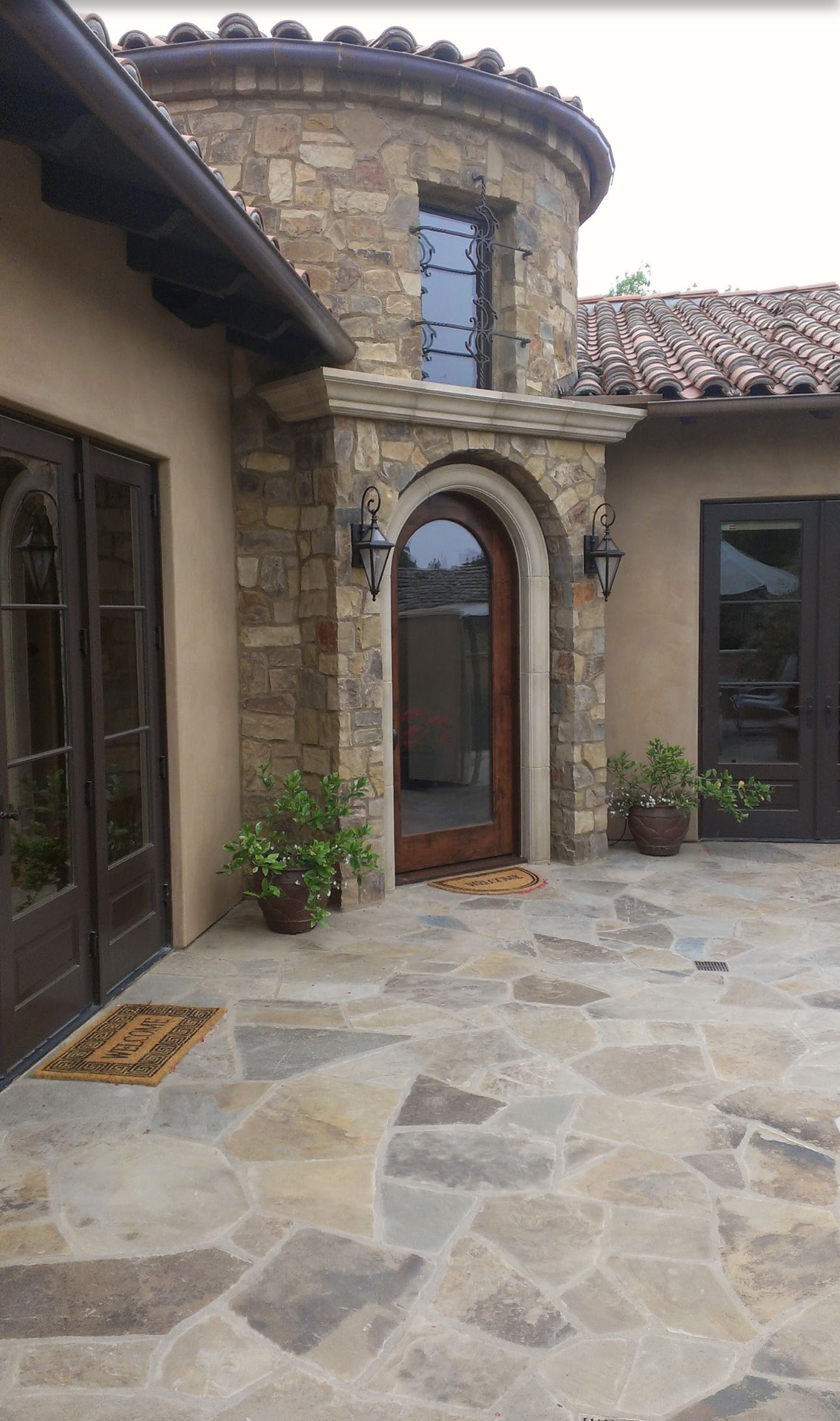 There is a stone patio in front of a house with a wooden door.