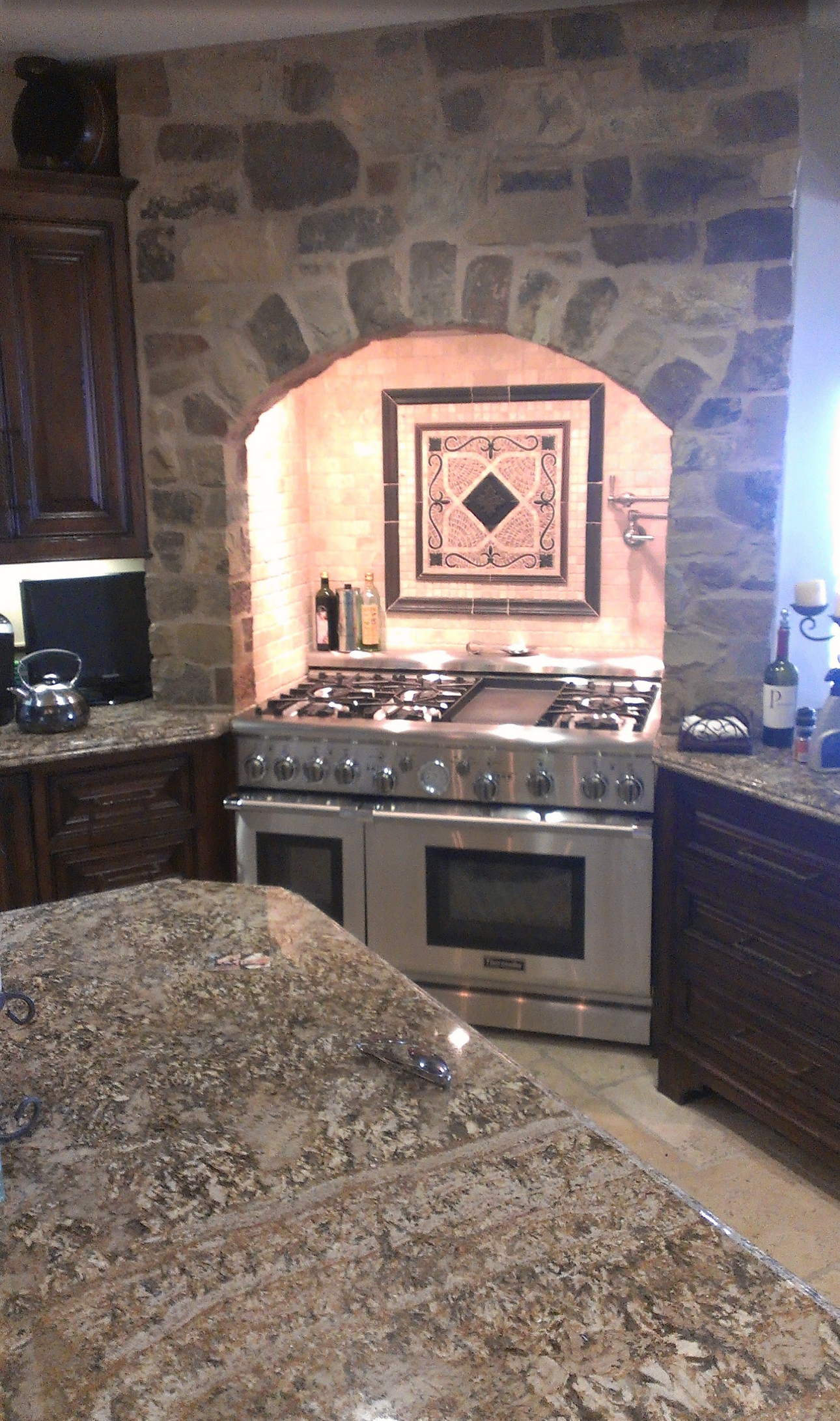 A kitchen with a stone wall and a stove and oven