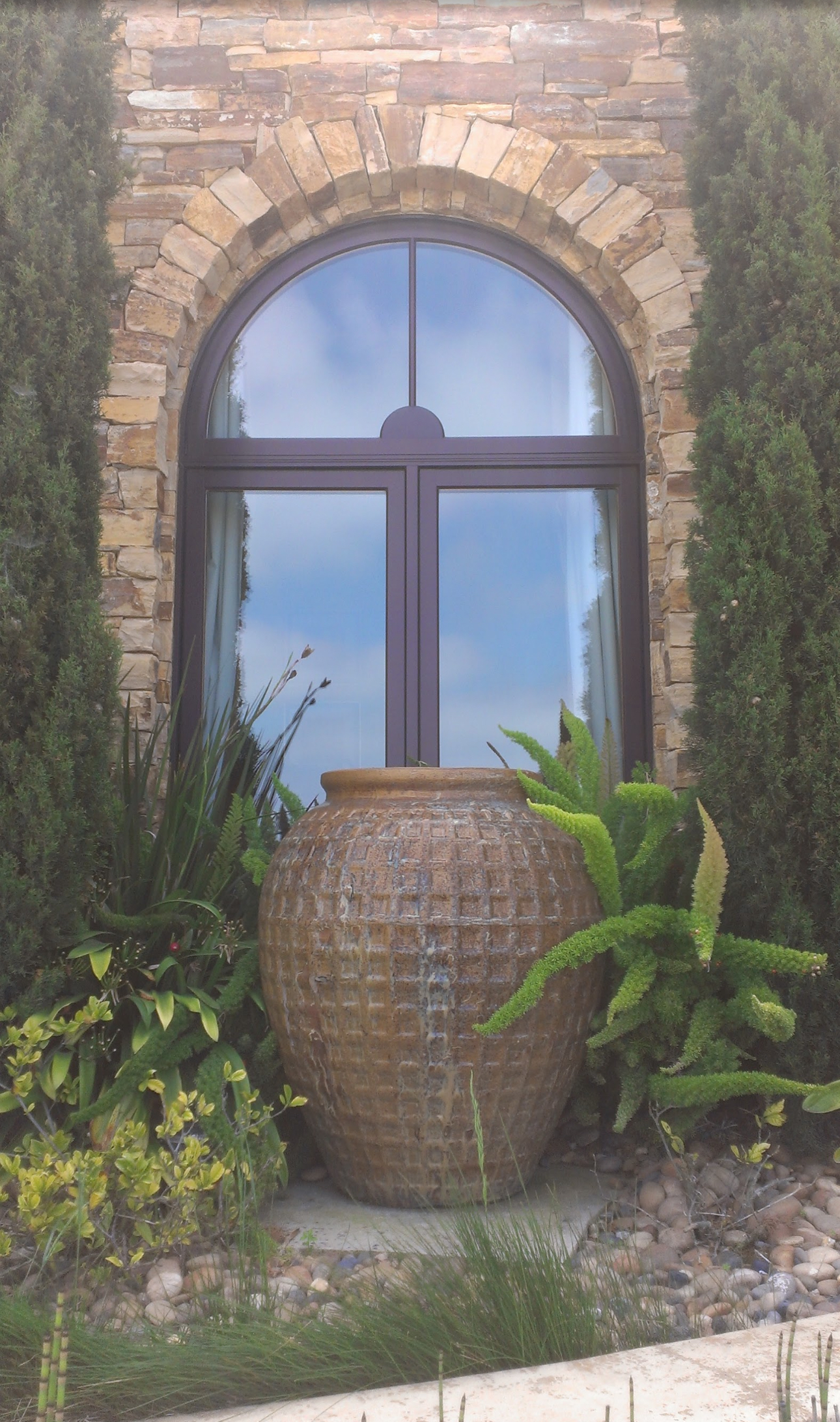 A large wicker pot is sitting in front of an arched window.