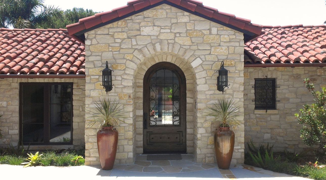 A large stone house with a red tile roof