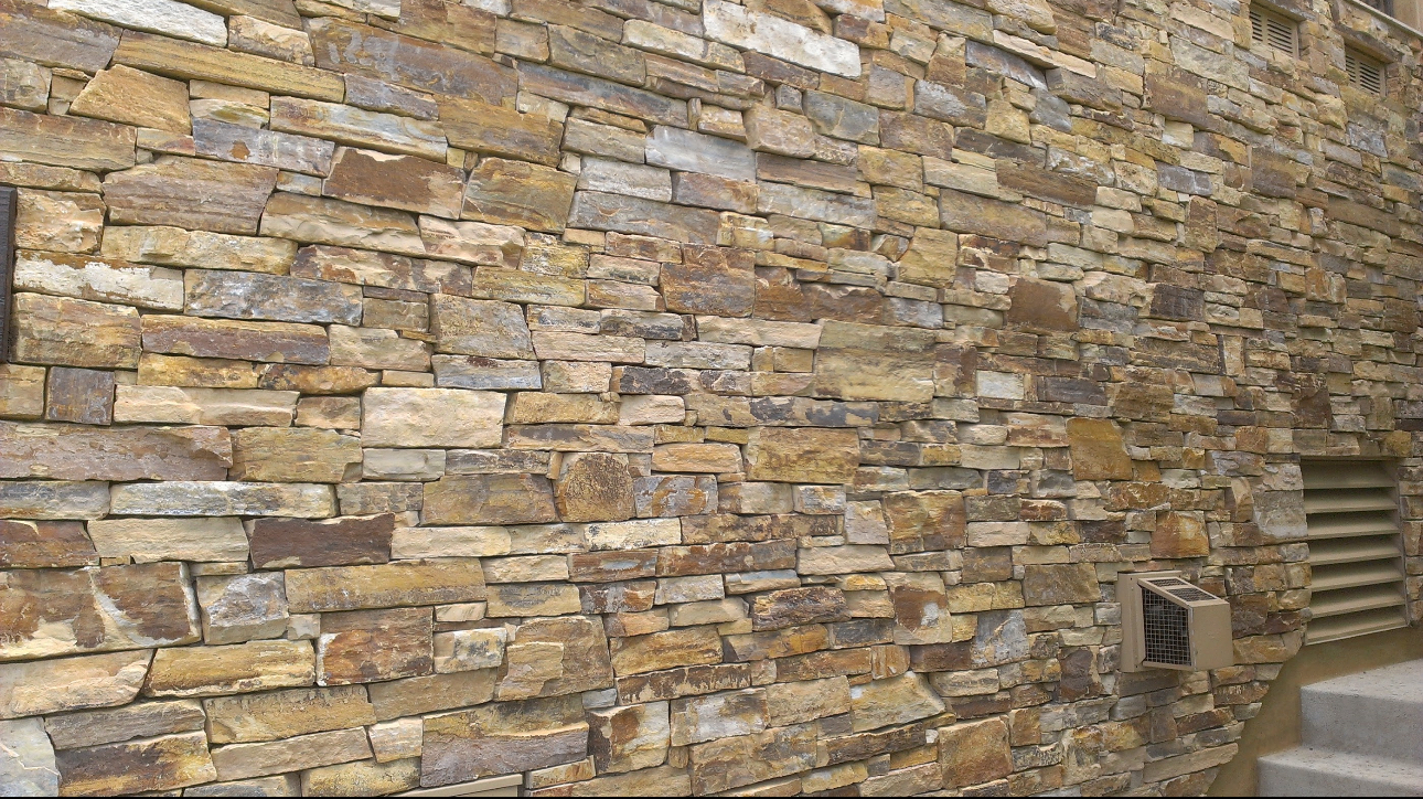 A large stone wall with a vent on the side of it.