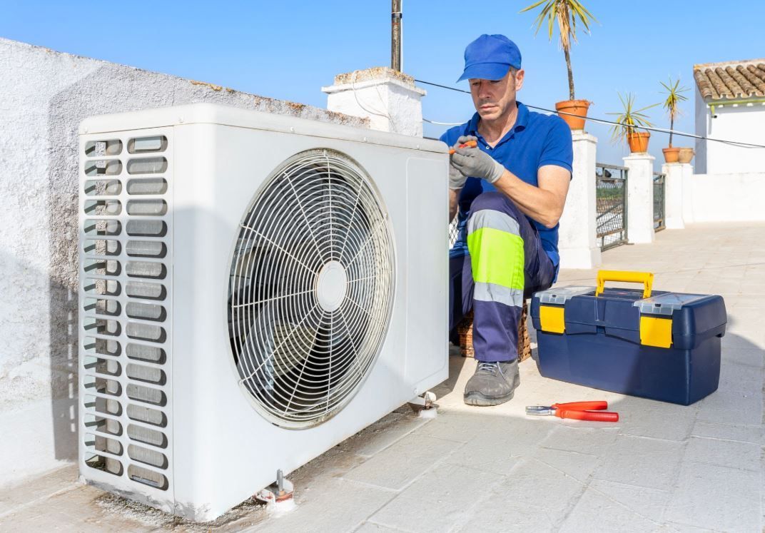 HVAC technician inspecting outdoor air conditioner condenser unit during an AC repair service
