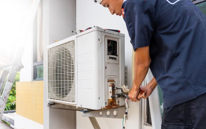 HVAC technician servicing an outdoor air conditioner unit for Fort Pierce HVAC repair