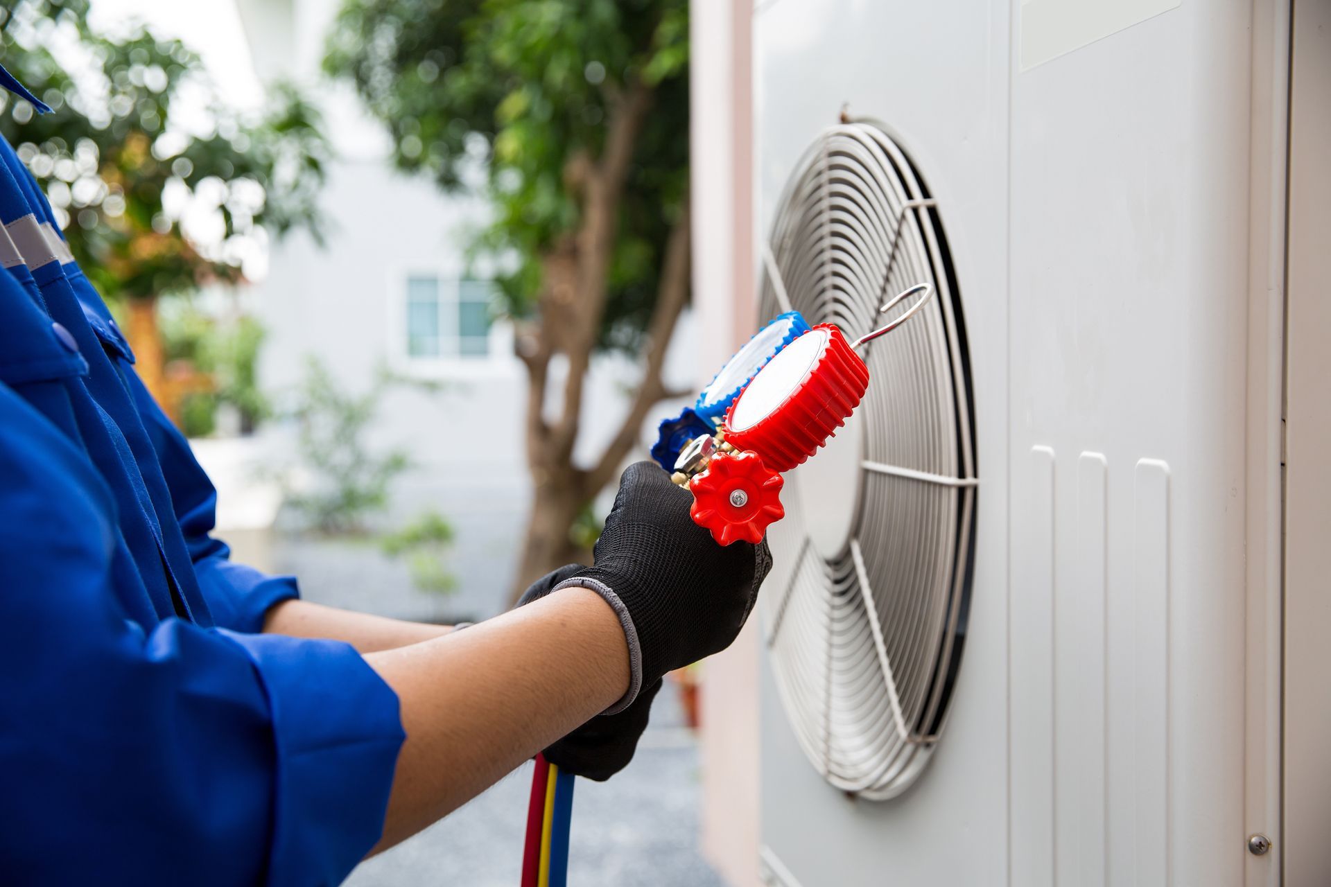 Technician cleaning an outdoor air conditioner unit with a brush and hose