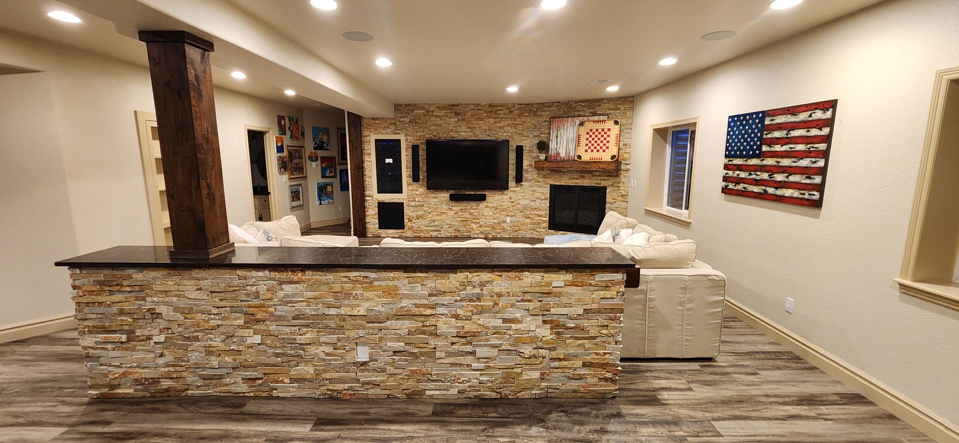 A finished basement with a stone wall behind a television and an American flag on the wall.
