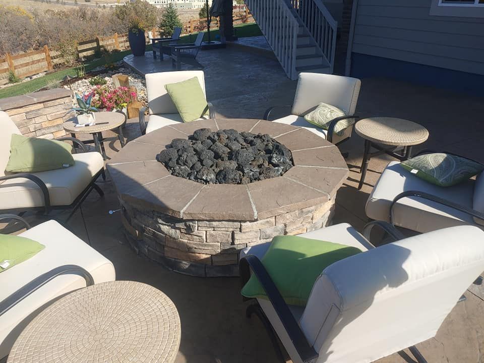 Outdoor seating area with fire pit surrounded by chairs and small tables.
