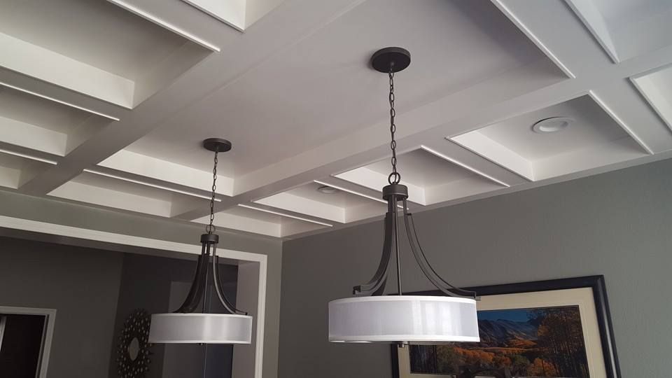 Two pendant lights hanging from a white coffered ceiling in a gray-walled room.