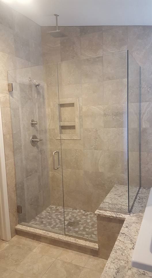 Glass shower with pebble floor, beige tile walls, and a built-in bench.