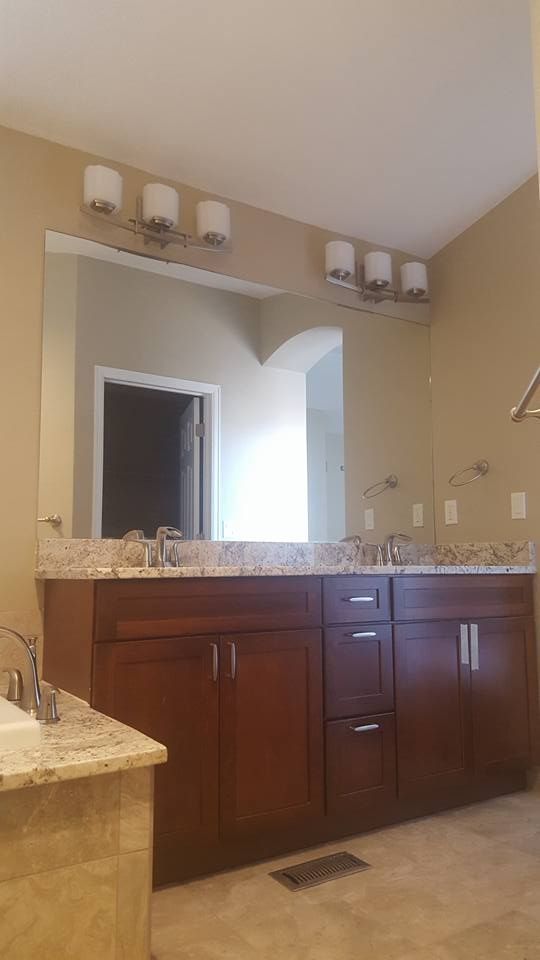 Bathroom with dark brown cabinets, granite countertops, large mirror, and overhead lights.