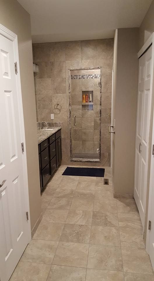 Bathroom with a walk-in shower, dark vanity, and two white doors.