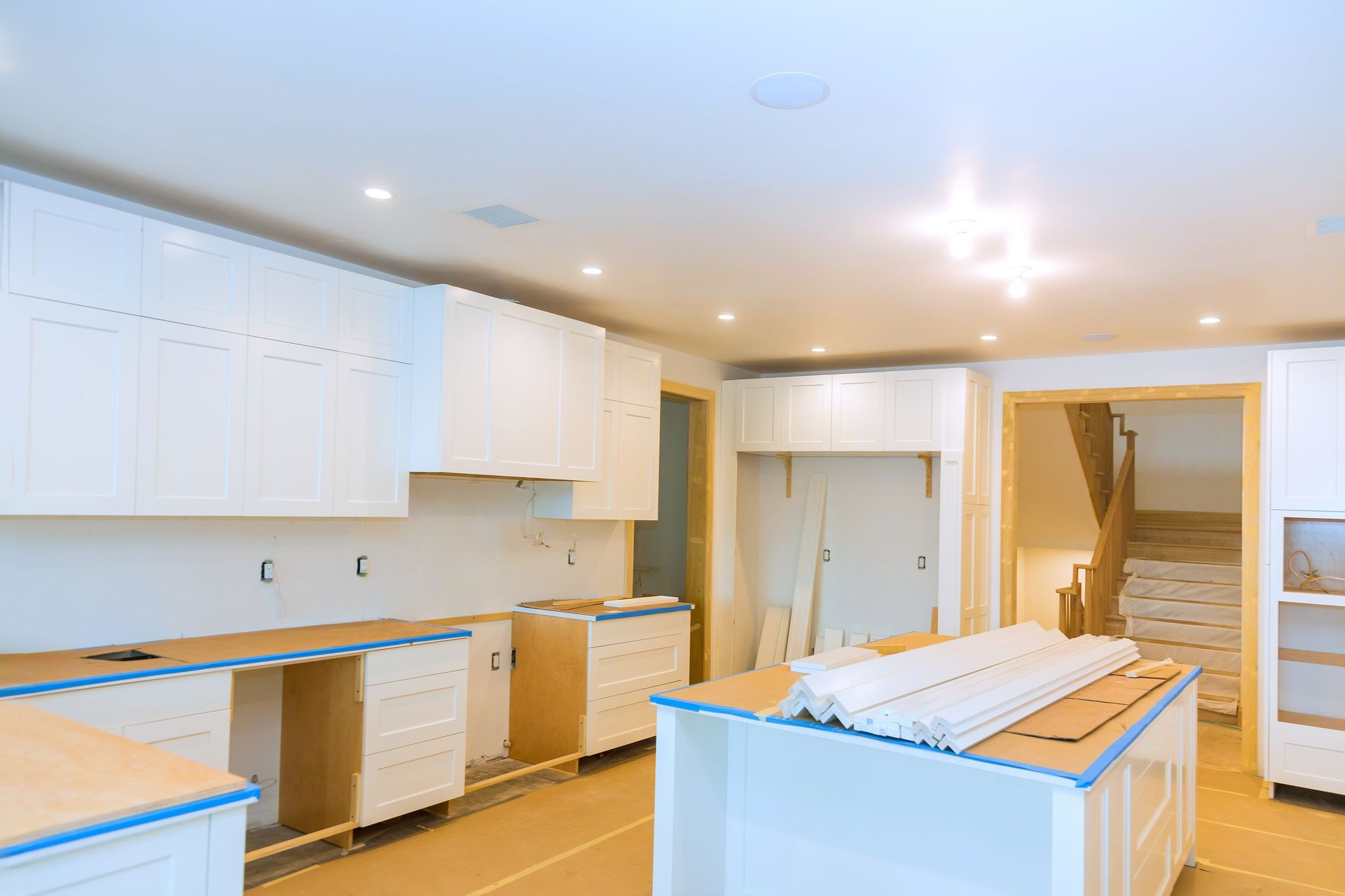 Kitchen remodel in progress with white cabinets, light wood counters, and a center island.