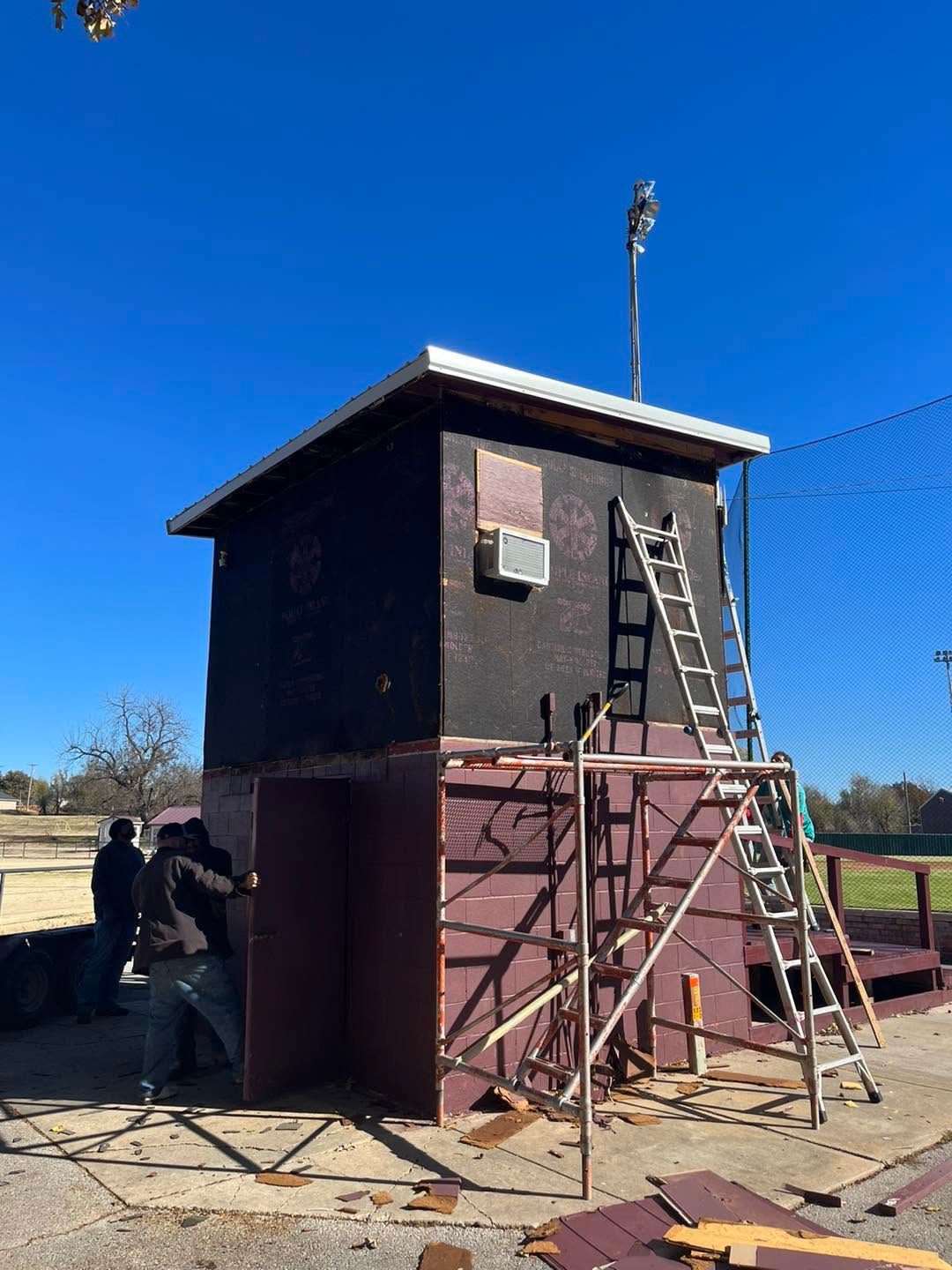 Small dark utility tower with ladder and scaffolding under a clear blue sky