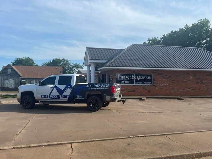 White utility truck parked outside a brick office building on a sunny day