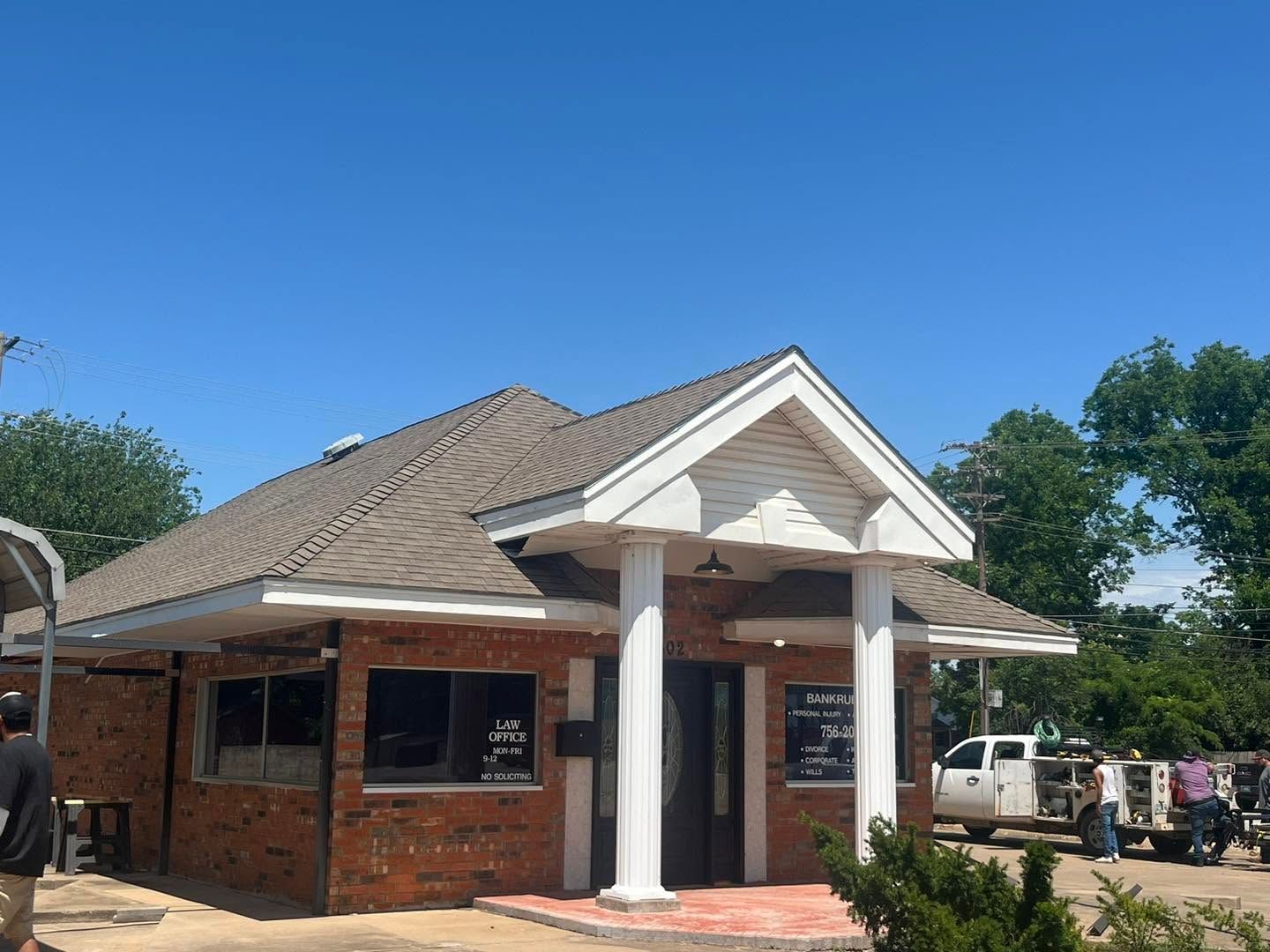 Small brick building with white columns and a gray roof under a clear blue sky