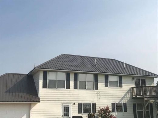 Two-story white house with dark gray roof and a small balcony under a clear sky