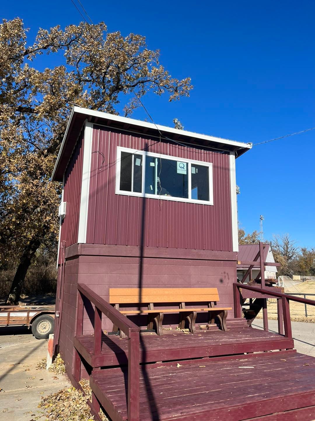 Small maroon shed with porch steps and windows on a sunny day