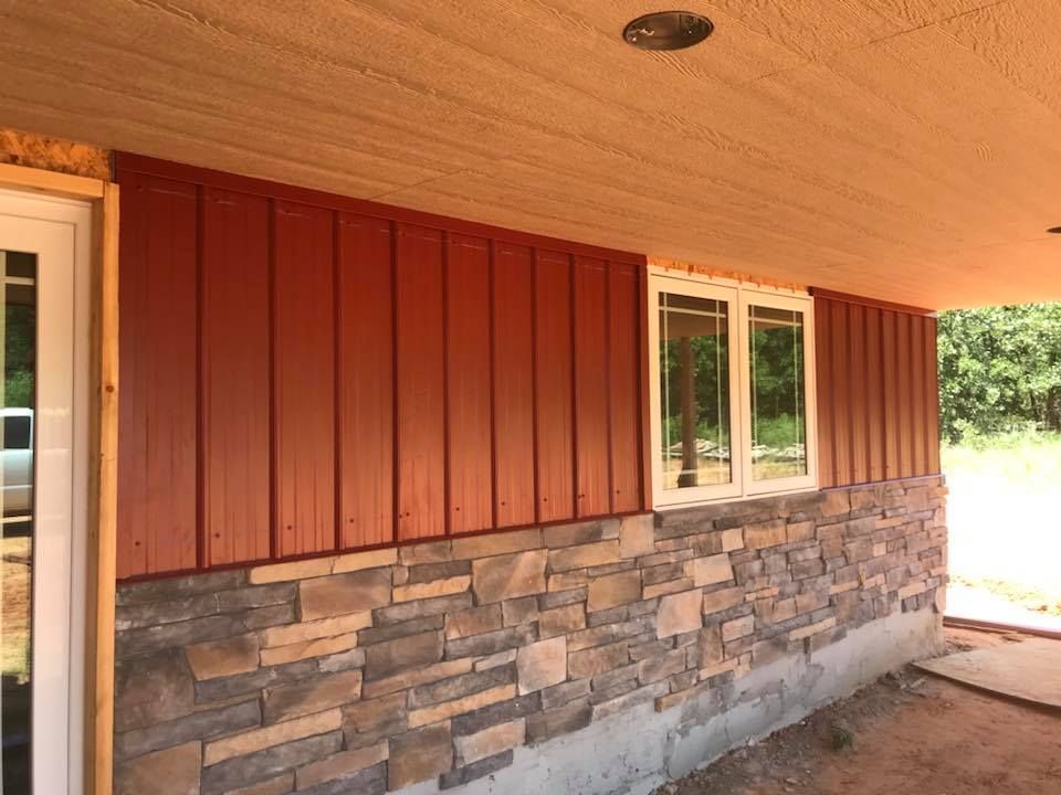Red and stone exterior wall with windows under a covered porch