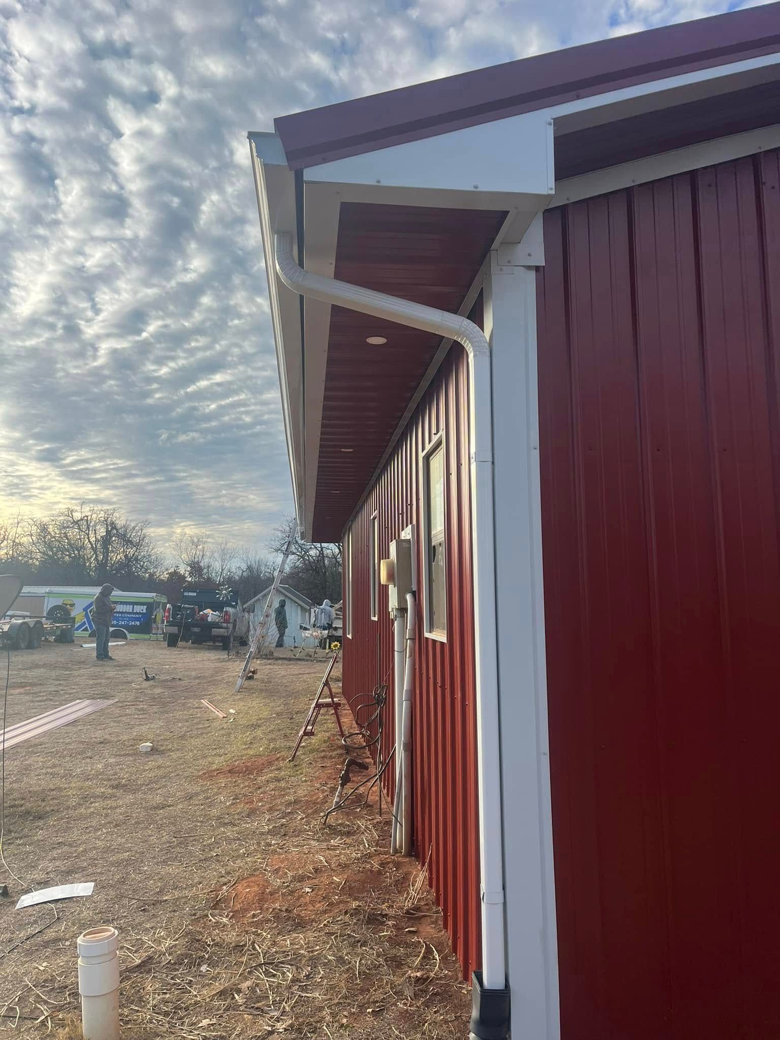 Red building with white trim along a rural roadside under a cloudy sky
