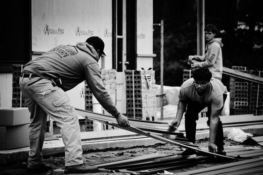 Two workers smoothing wet concrete on a construction site