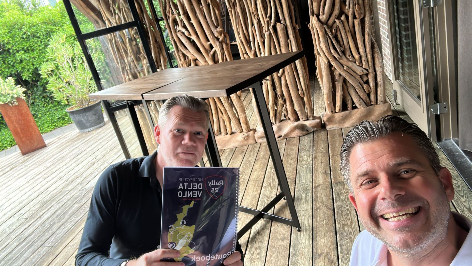 Twee mannen houden een boek met de titel