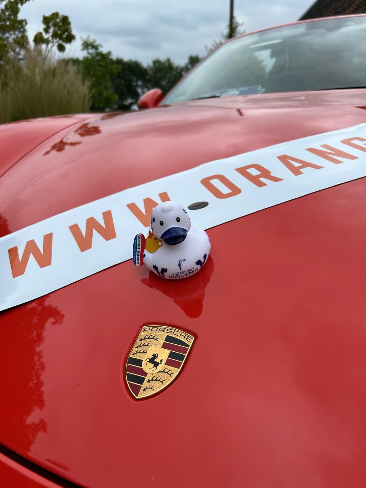 Rode Porsche met een badeendje op de motorkap. Op een banner staat