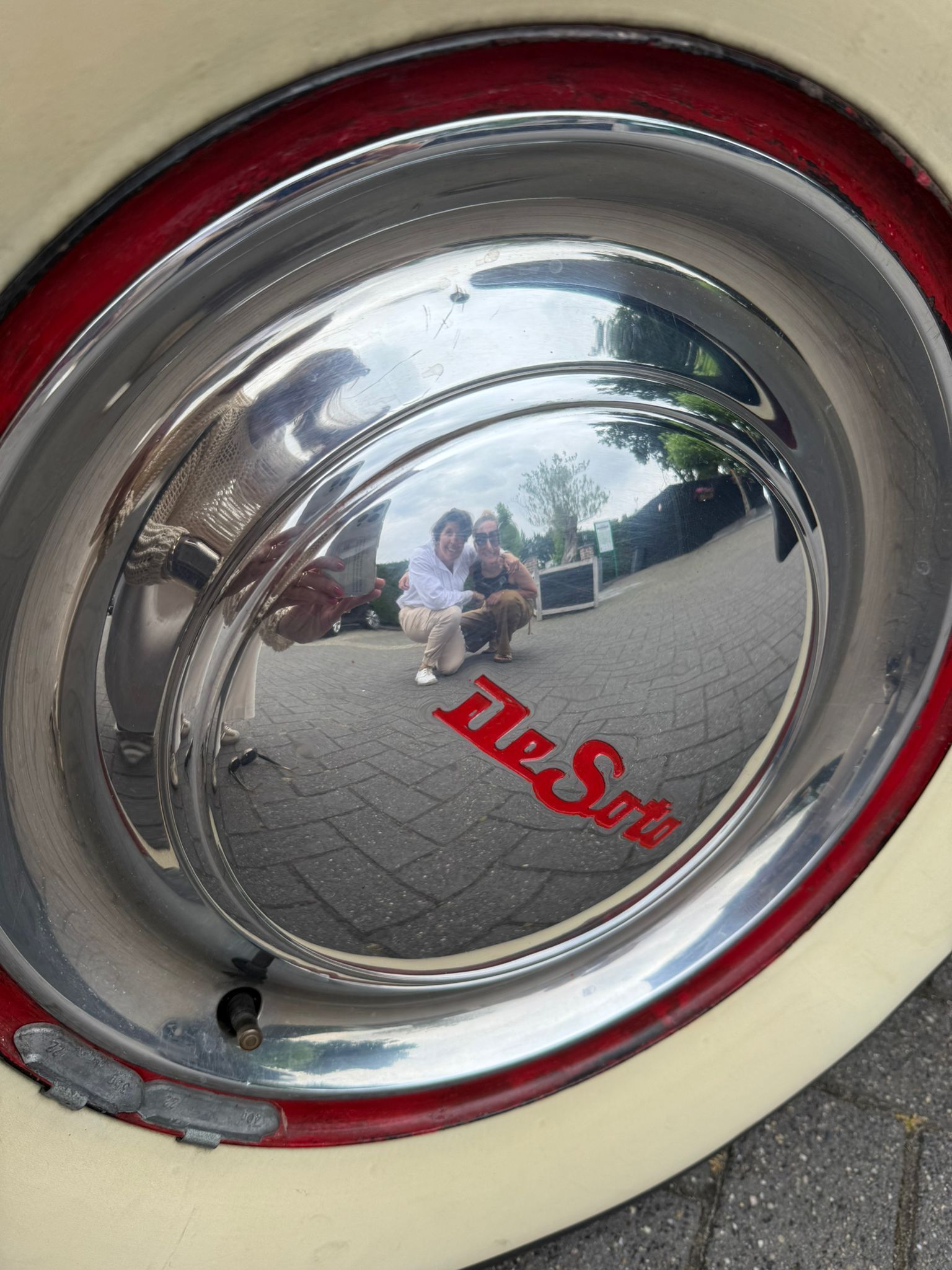 Close-up van een wieldop die twee personen weerspiegelt. Rood en zilver met de woorden