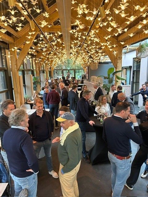 Mensen die gezellig samen zijn in een moderne ruimte met houten balken en vogelvormige lampen.