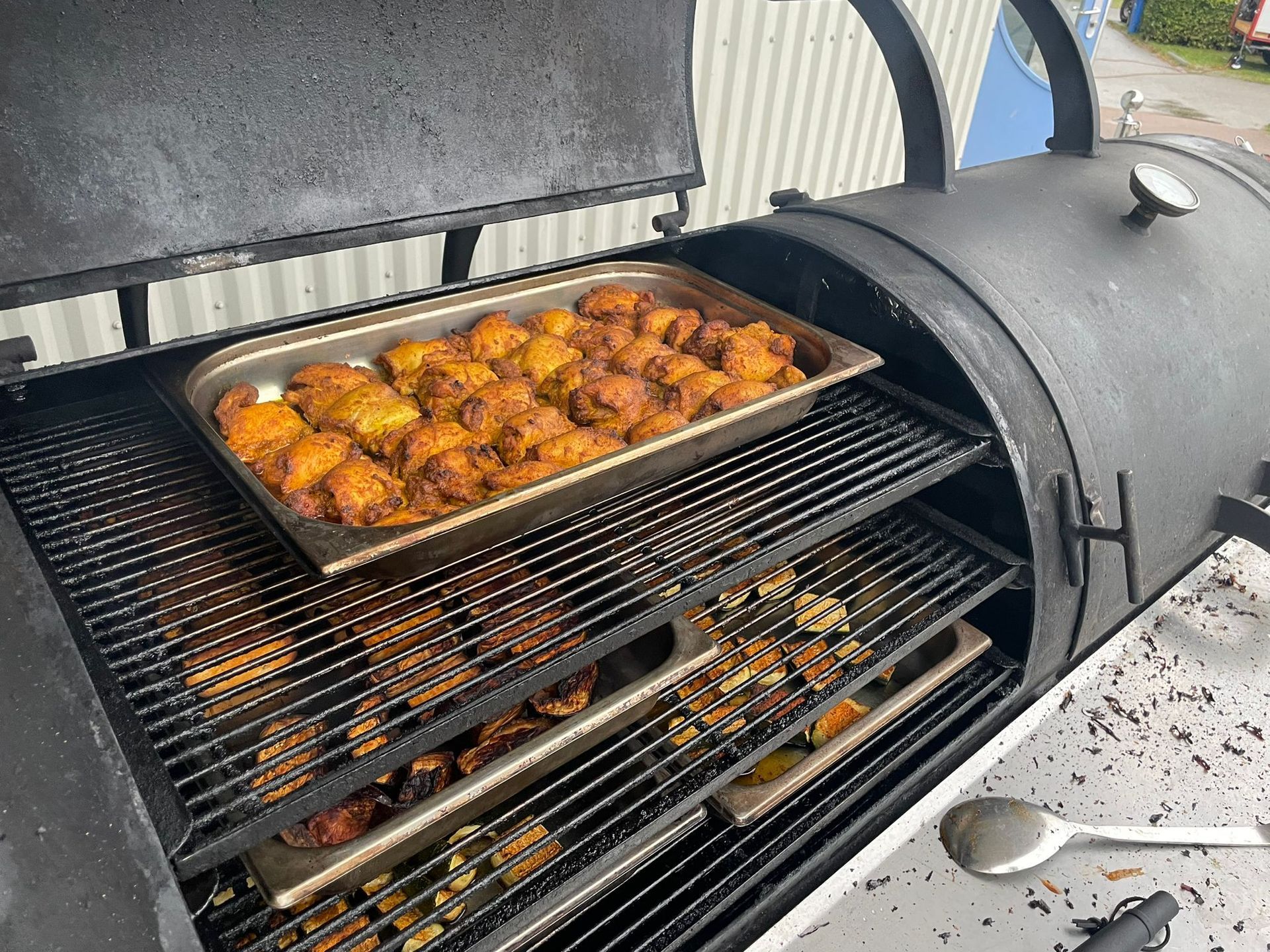 Rookgrill met schalen voor bereid voedsel. Grote, zwarte buitengrill voor het bereiden van kip en ander vlees.