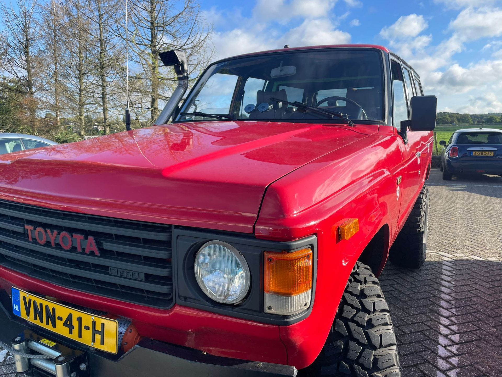Rode Toyota Land Cruiser met snorkel en offroadbanden, buiten geparkeerd.