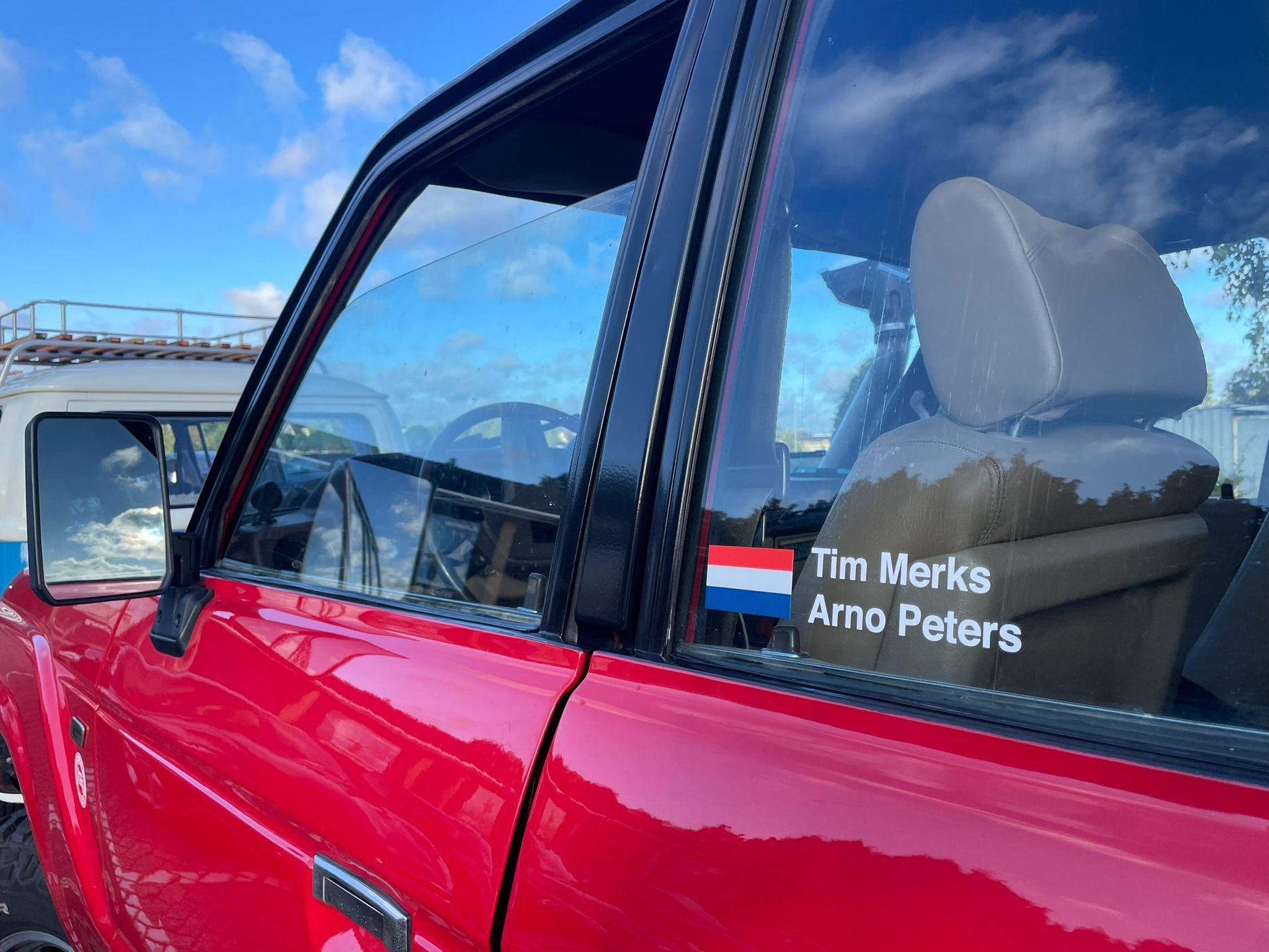 Rode klassieke SUV met Nederlandse vlagsticker; namen 