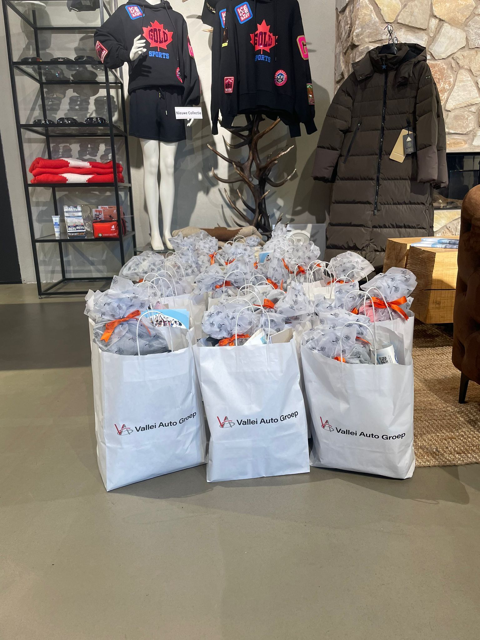 Witte boodschappentassen met oranje strikken, in een winkel met uitgestalde kleding.